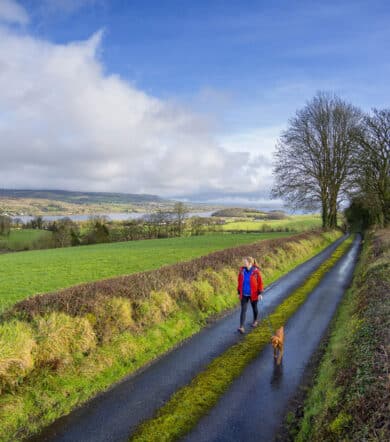 Woman and Dog hiking the Cavan Way and the Beara Breifne Way with Lough MacNean in the background.