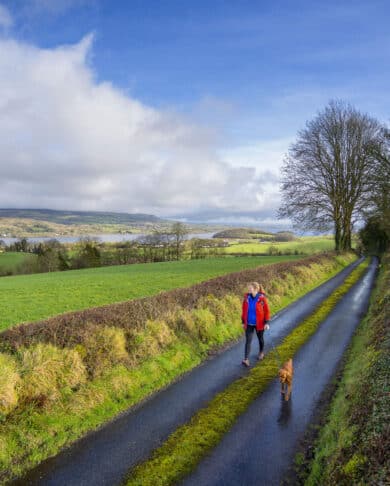 Woman and Dog hiking the Cavan Way and the Beara Breifne Way with Lough MacNean in the background.