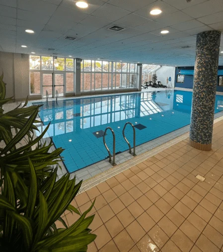 Inviting indoor swimming pool with lounge chairs and panoramic windows at hotel, offering relaxation and leisure.