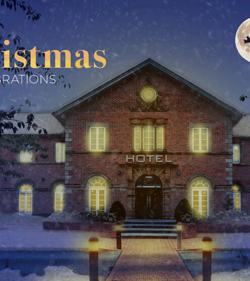 Elegant brick hotel with festive lighting, moonlit snowy grounds, and Santa sleigh sky silhouette, celebrating Christmas.