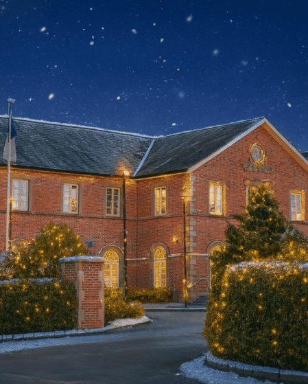 Charming brick hotel with lit trees, moonlit snowy night, Cavan Crystal Hotel sign, festive and inviting entrance.