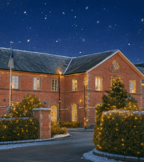 Charming brick hotel with lit trees, moonlit snowy night, Cavan Crystal Hotel sign, festive and inviting entrance.