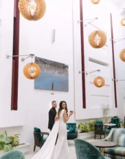 Couple in elegant hotel lounge with high ceilings and modern decor, showcasing ambient lighting and lush greenery.